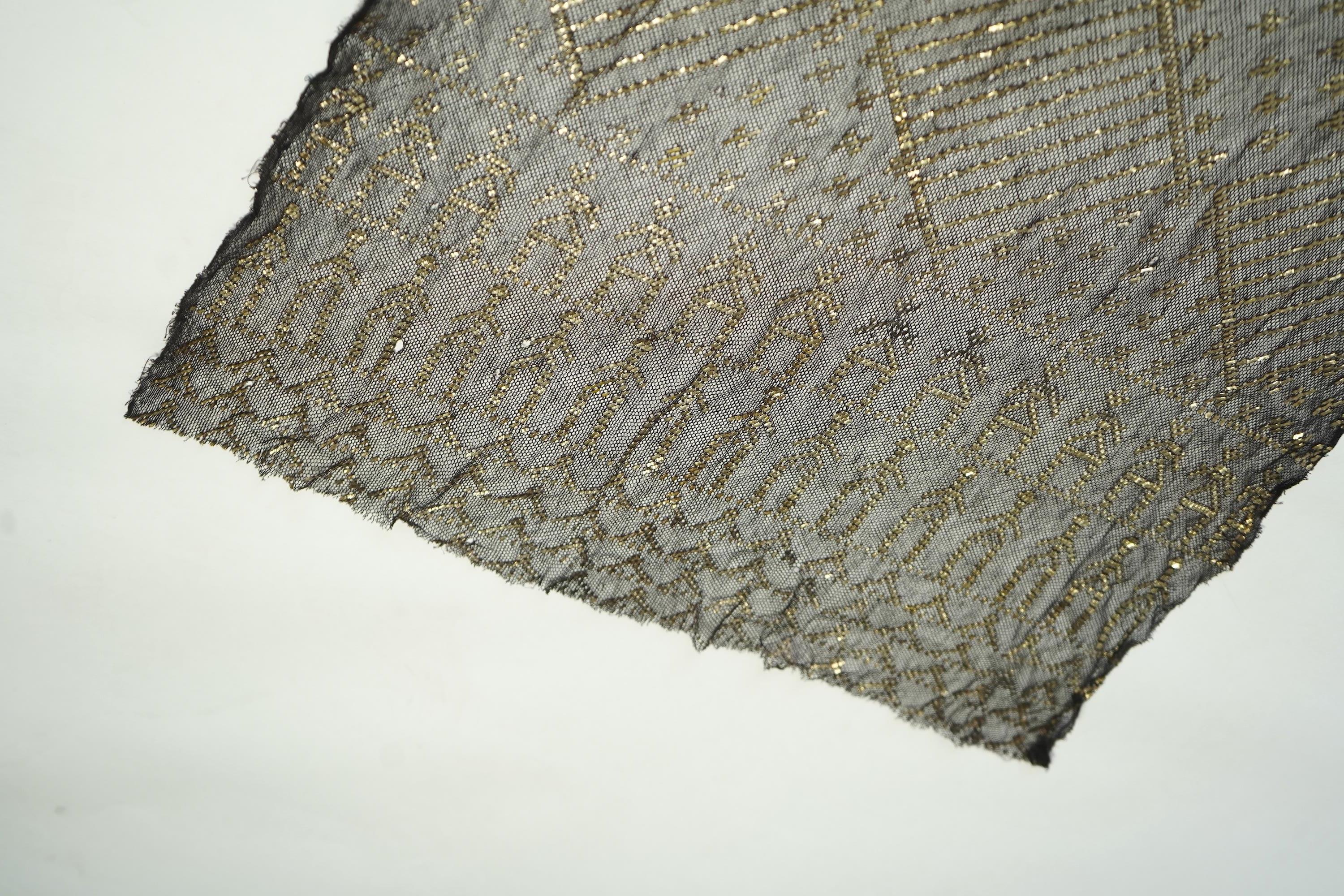A 1930’s Egyptian decorative metal on black net evening stole. Approximately 218cm long. Condition - the rolled edges are frayed but the colour and design are intact.